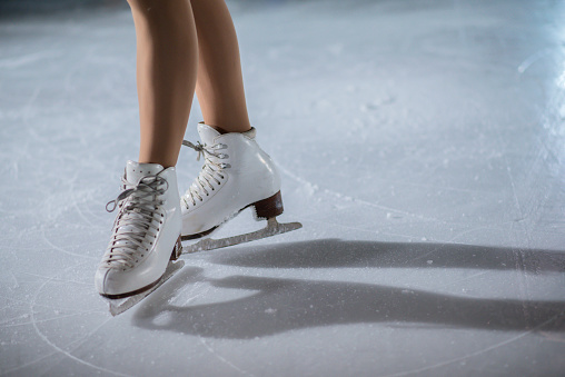 Gorgeous ice skates on the ice rink on a young girl's feet.