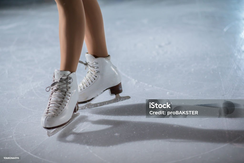 White skates on the ice rink Gorgeous ice skates on the ice rink on a young girl's feet. Figure Skating Stock Photo