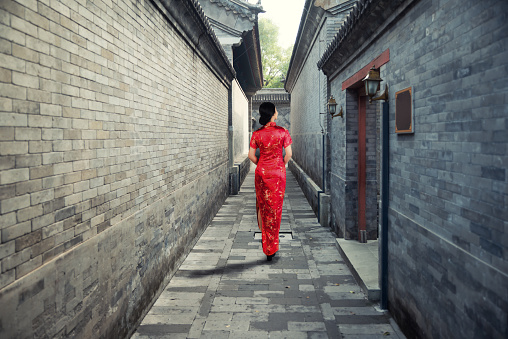 Asian young woman in old traditional Chinese dresses in Hutong village in Beijing, China.