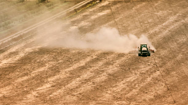 Aerial view of a tractor ploughing a large field in sunshine, California, USA.