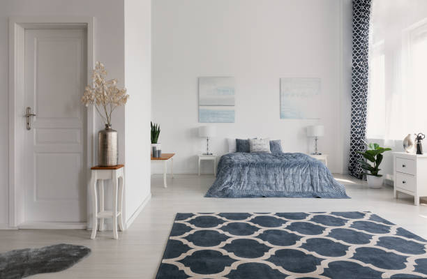 istock Patterned carpet in spacious bedroom interior with plant on table and posters above bed. Real photo 1068271614