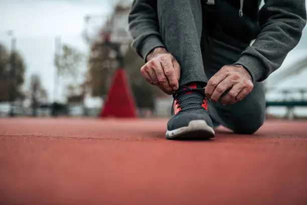 Tying shoelaces before a run on stadium. Low angle image.