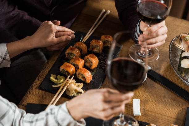 istock Partial view of couple holding hands while drinking wine and eating sushi in restaurant 1068293280