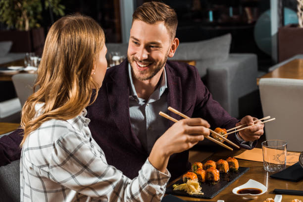istock Beautiful happy couple eating sushi rolls in restaurant 1068293432