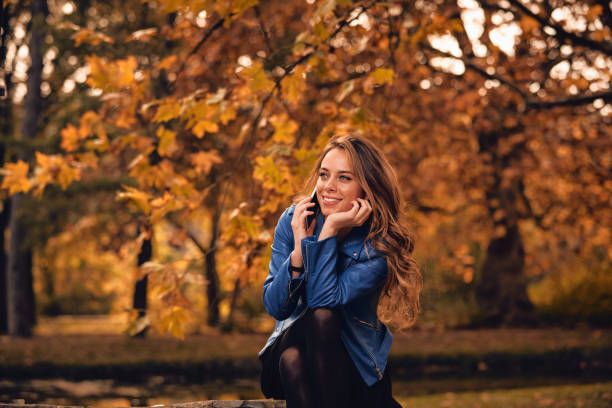istock Cute girl using cellphone in park with autumn colors. 1068295348