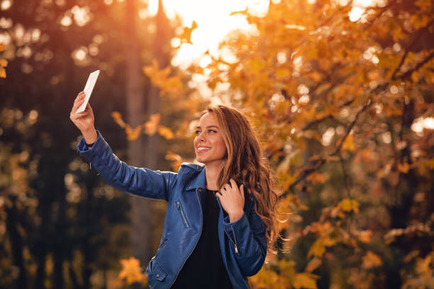 istock Cute girl using cellphone in park with autumn colors. 1068303348