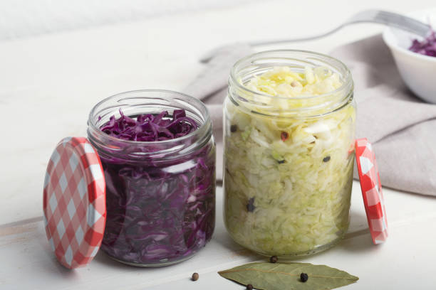 Purple and white cabbage in jars on a wooden table