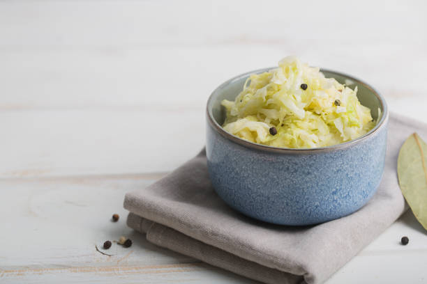 木製のテーブル上に青いボウルにザワークラウト - sauerkraut coleslaw cabbage plant ストックフォトと画像