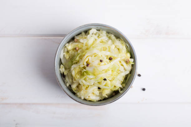 sauerkraut in einer blauen schüssel auf einem holztisch - sauerkraut salad coleslaw cabbage stock-fotos und bilder