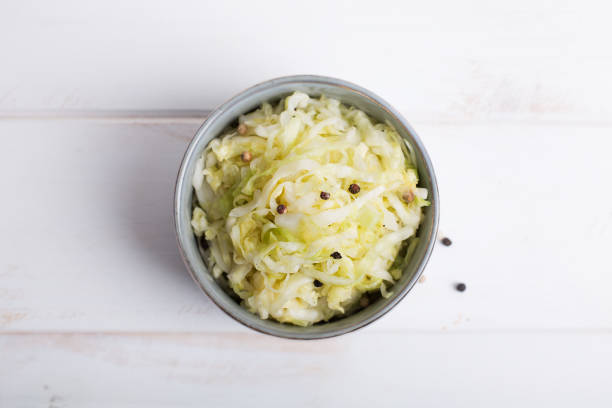 木製のテーブル上に青いボウルにザワークラウト - sauerkraut coleslaw cabbage plant ストックフォトと画像