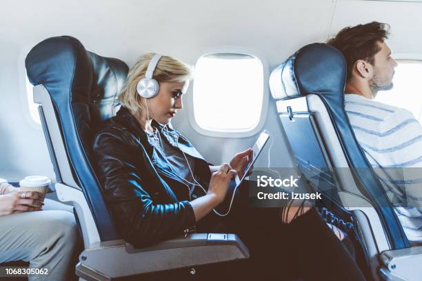 Female Passenger Using Digital Tablet During Flight Stock Photo - Download Image Now