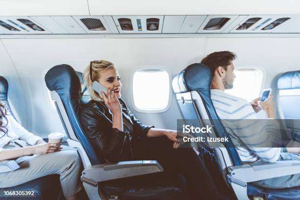 Female Passenger Talking On Mobile During Flight Stock Photo - Download Image Now - Adult, Air Vehicle, Airplane
