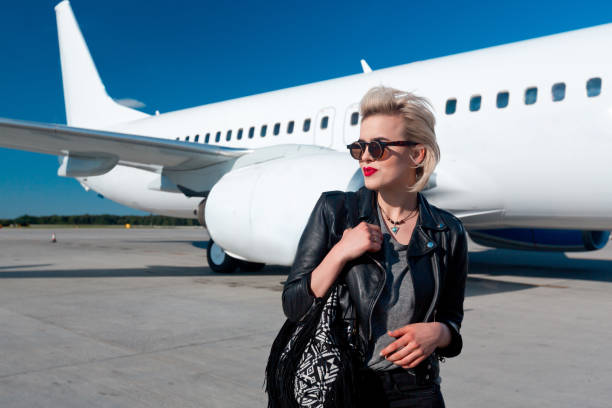 istock Attractive woman in front of airplane 1068313200