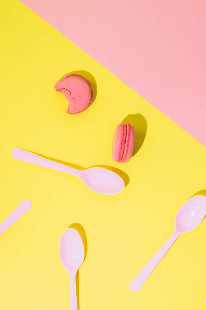 istock Pink almond cookies macarons or macaroons with plastic spoons on yellow background. 1068314728