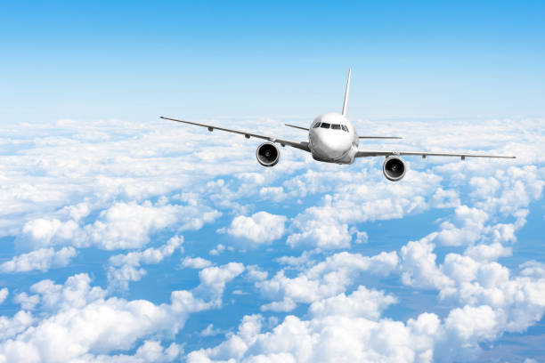 istock Airplane jet flying at flight level high in the sky above the clouds and blue sky. 1068332032