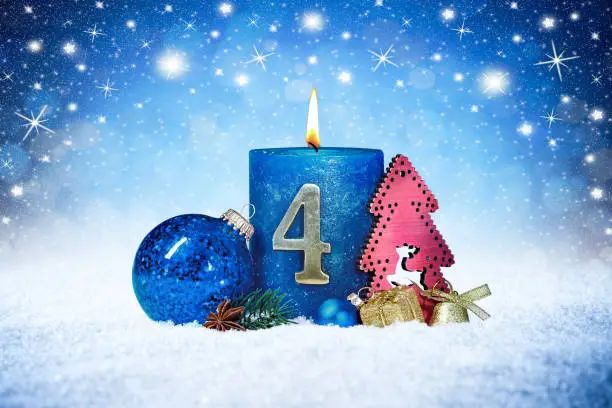 fourth sunday of advent blue candle with golden metal number red decoration one on wooden planks in snow front of silver panorama bokeh background