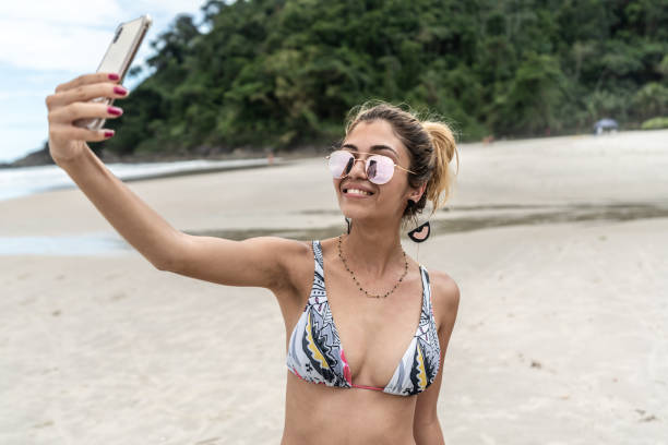istock Beautiful Woman taking a selfie at beach 1068343384