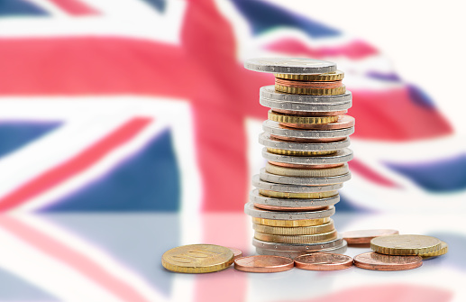 Coins stacked on each other in different positions with United kingdom flag