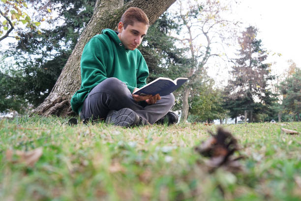 istock Young man reading book in park 1068358966