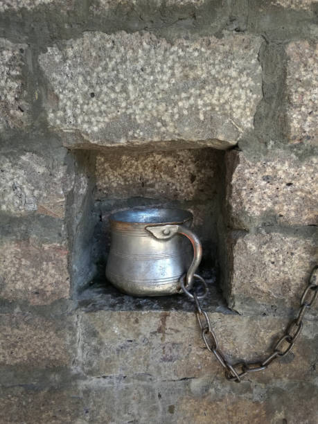 istock Chained metal cup for water in the niche. 1068359156
