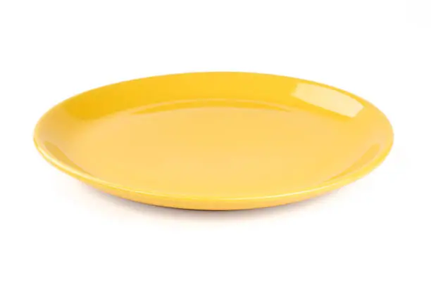 Pastel yellow colored plate isolated on white background, front view, clipping path, without the cast shadow, included.