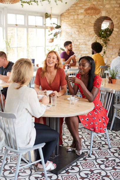 Three female friends talking over brunch at a cafe, vertical