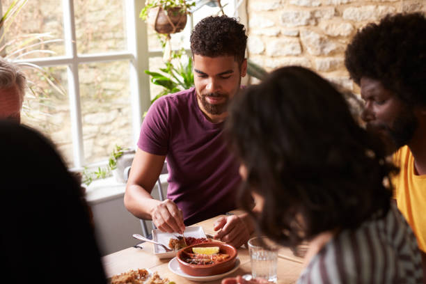 istock Young mixed race man eating with friends at a dining table 1068362234