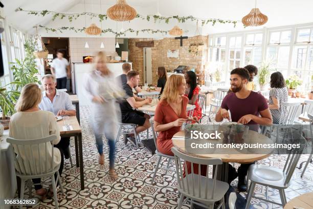 Clientes De Mediodía Comiendo En Un Restaurante Ocupado Foto de stock y más banco de imágenes de Restaurante