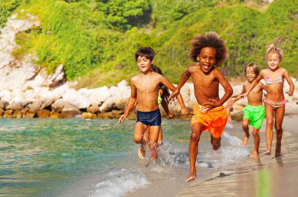 istock Happy multiethnic kids running along sandy beach 1068363012