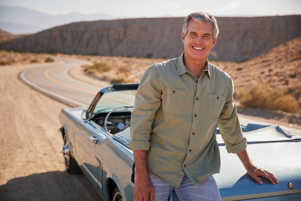 istock Senior white man leaning on open top car at desert roadside 1068364692