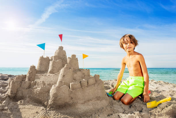 istock Happy boy building big sand castle on the beach 1068364780