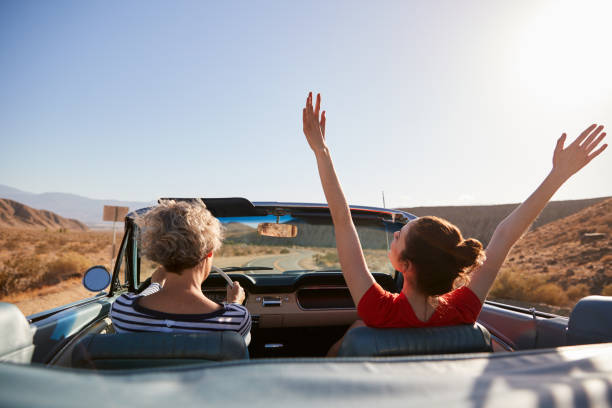 istock Mum driving car, daughter with hands in the air, back view 1068364862