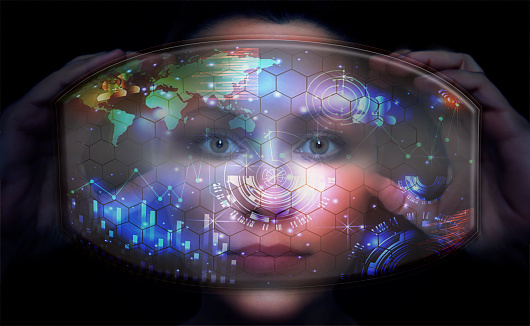 Close-up portrait of young and beautiful woman with the virtual futuristic glasses ( technology concept).Virtual holographic interface and young woman wearing glasses
