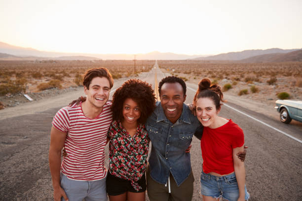 istock Four friends on a desert highway smiling to camera, close up 1068368388