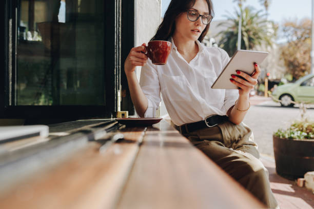 бизнесвумен, используя цифровую планшет и пью кофе в кафе - e reader digital tablet cafe reading стоковые фото и изображения