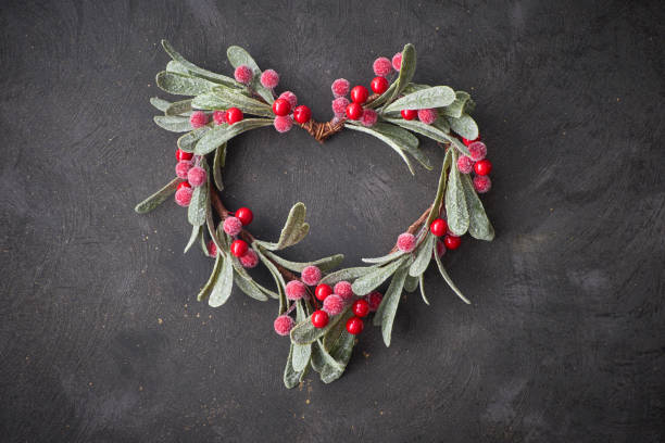 istock Christmas decorative heart made from red mistletoe berries and leaves on dark 1068372592