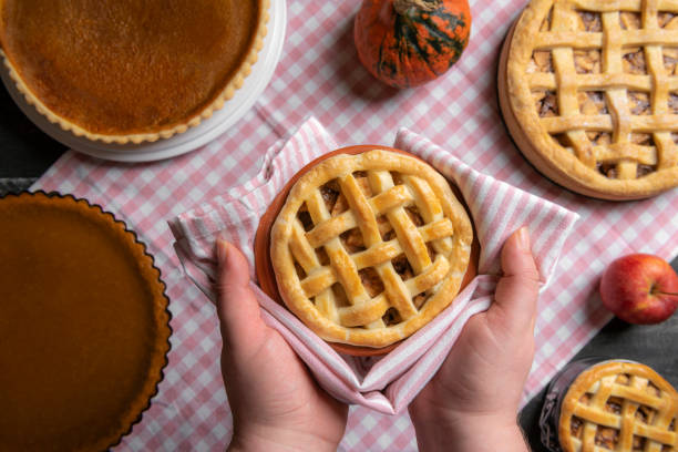 istock Apple pie held in hands over a table with many pies. Sweet pies baking. Above view 1068373164