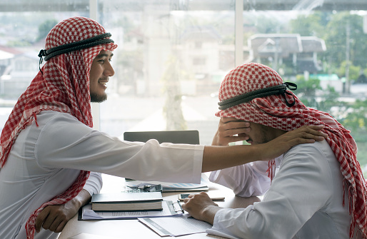 Arabian man comforting friend in office because receiving bad news and crying