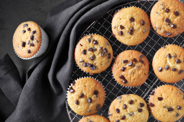 istock Freshly baked choco chip muffins cooling off on wire mesh on dark background with linen towel 1068383962