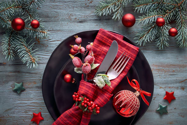 Flat lay with Xmas decorations in green and red with frosted berries, trinkets, plates and crockery stock photo