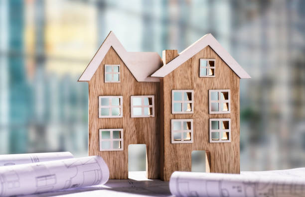 istock Two wooden houses with blueprints 1068391154