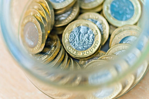 istock Pile of one pound coins in a jar 1068393896