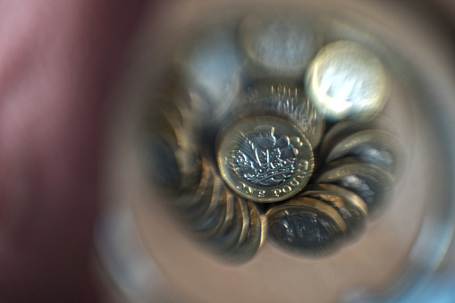 Pile of one pound coins in a jar viewed through a sphere tail side up.