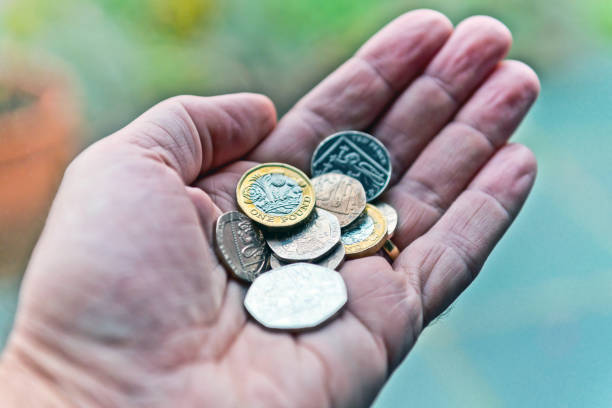 una mano che tiene le monete britanniche - one pound coin coin currency british culture foto e immagini stock