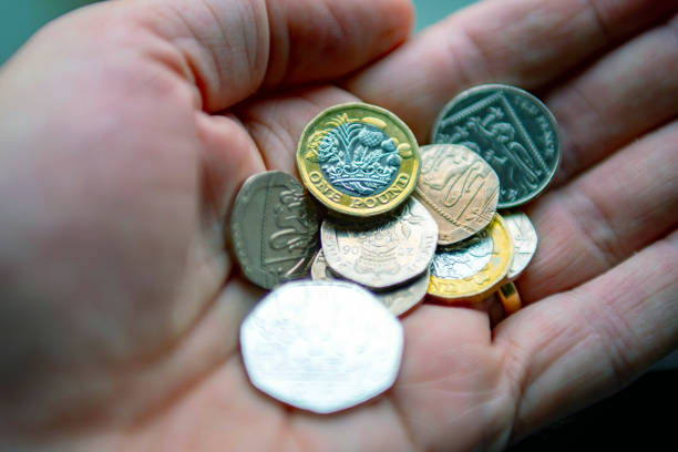 una mano che tiene le monete britanniche - one pound coin coin currency british culture foto e immagini stock