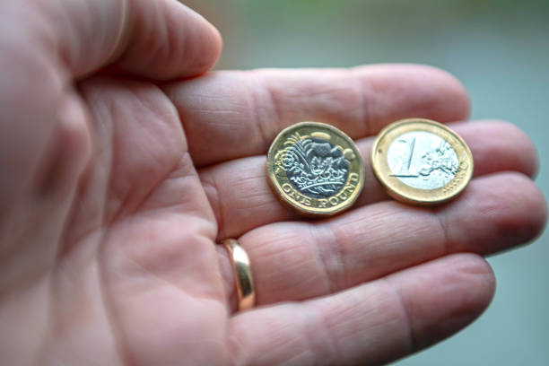 istock A hand holding one Euro coin and one pound coin 1068394810