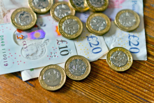 British currency on  a table British currency, ten and twenty pound notes and pound coins on a dining table. twenty pound note stock pictures, royalty-free photos & images