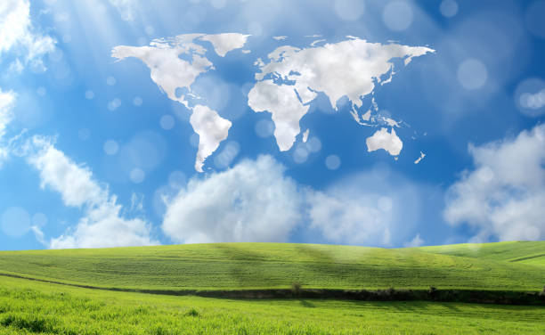 istock Green grass rolling landscape and world map shaped clouds over sunny sky 1068404116