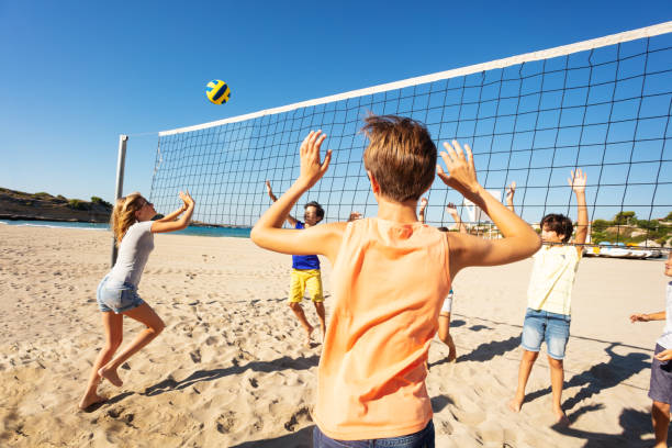 sportive jeune fille passant de volley-ball sur le net - beach volleying ball playing photos et images de collection