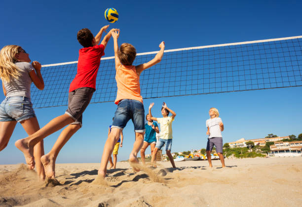 beach volleyball players jumping to spike the ball - beach volleying ball playing imagens e fotografias de stock